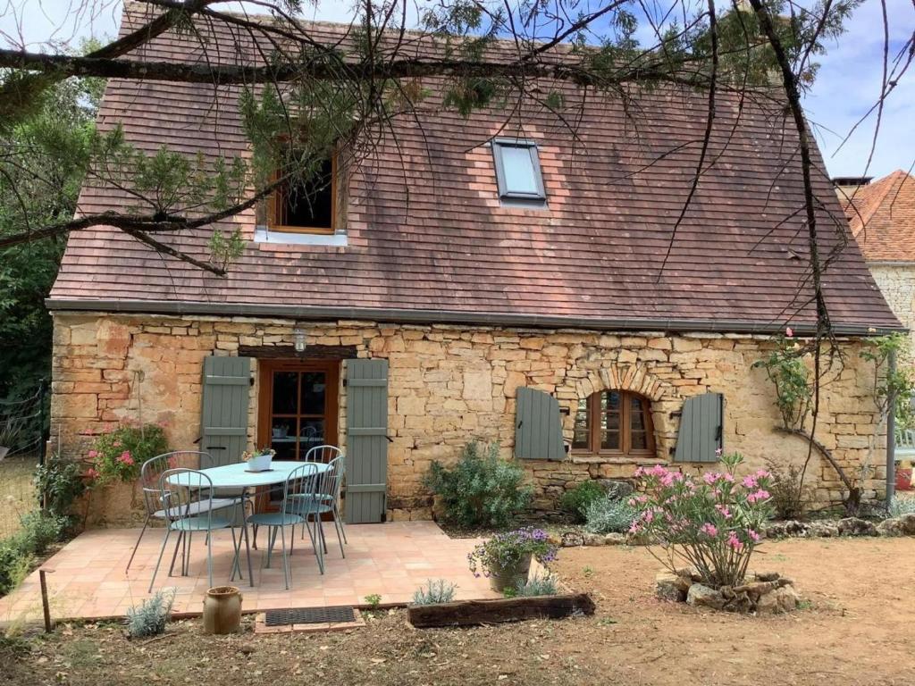 a stone house with a table and chairs in front of it at Gîte en Périgord avec piscine privée, animaux acceptés - FR-1-616-494 in Florimont-Gaumiers