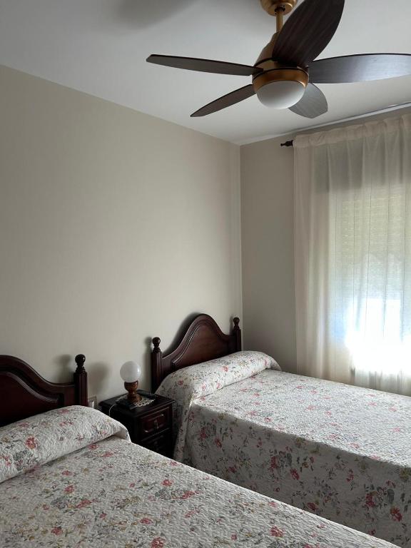 a bedroom with two beds and a ceiling fan at PENSIÓN* AS VIÑAS in Puebla del Brollón