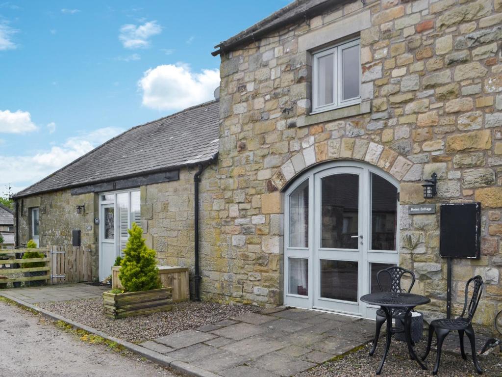 a stone house with a table and chairs in front of it at Heron Cottage in Alnham