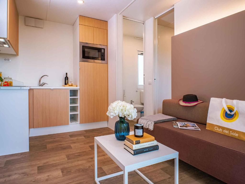 Una sala de estar con un sofá y una mesa con libros. en Mobilehomes in Foggia 53446, en Fossalòn