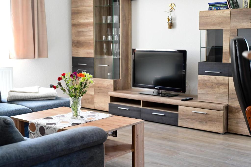 a living room with a tv and a vase of flowers at Ferienwohnung Zum Steiger in Bleicherode