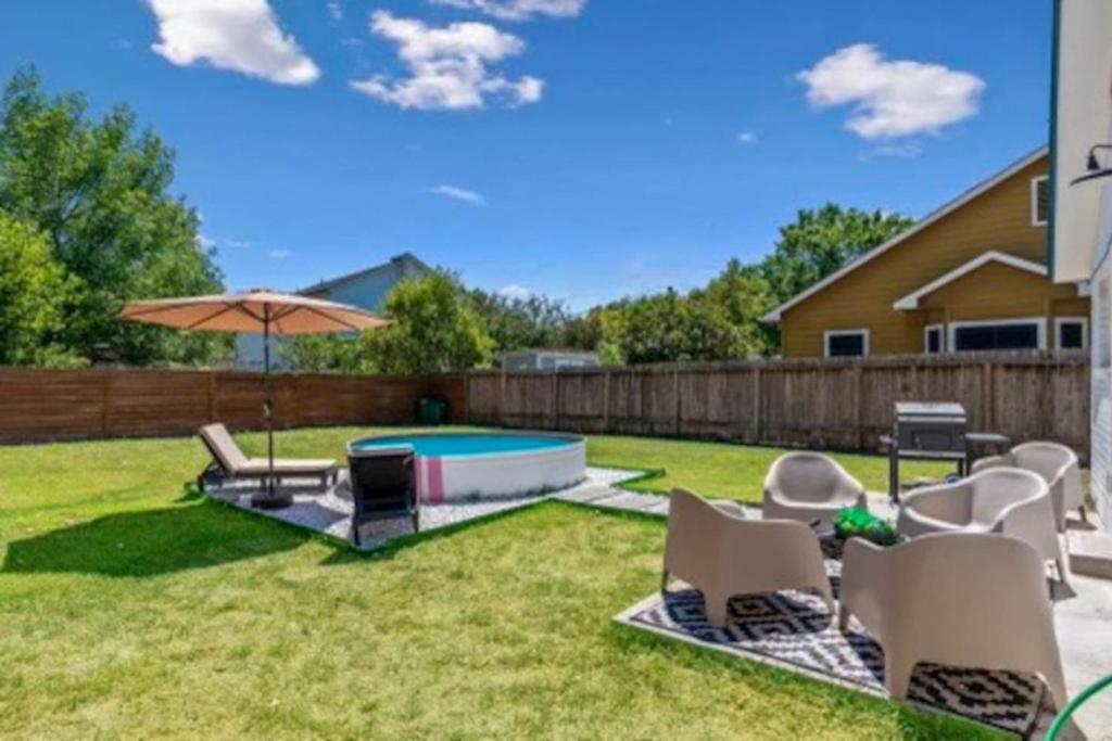 a backyard with a pool and chairs and an umbrella at 2 Combined Homes - 2 Private Pools - 16 Guests in Austin