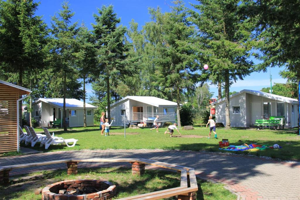 a group of people playing in a yard with mobile homes at Wojtek - domki letniskowe i pokoje, animacje, melex na plażę in Dziwnów