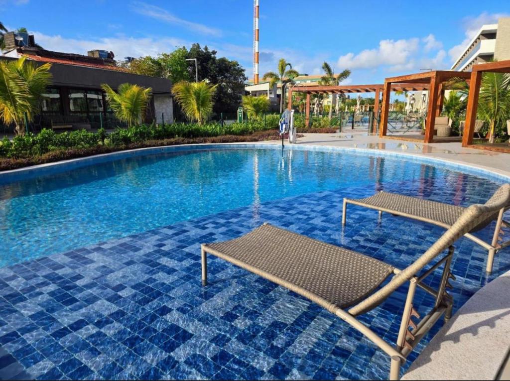 a swimming pool with two chairs in the middle at Beach Class Summer Slin Térreo Garden in Porto De Galinhas
