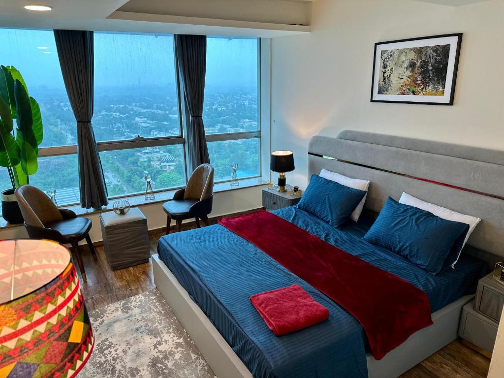 a bedroom with a blue bed and a large window at CENTAURUS ISB 2 BHK Plus Study in Islamabad