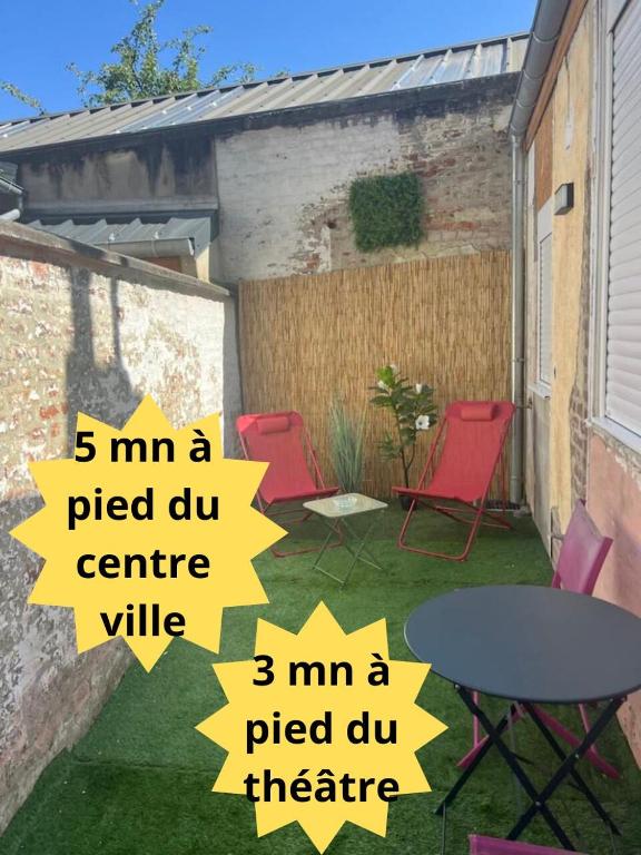 d'une terrasse avec quatre chaises rouges et une table. dans l'établissement Appartement en rez de chaussée avec extérieur, à Abbeville