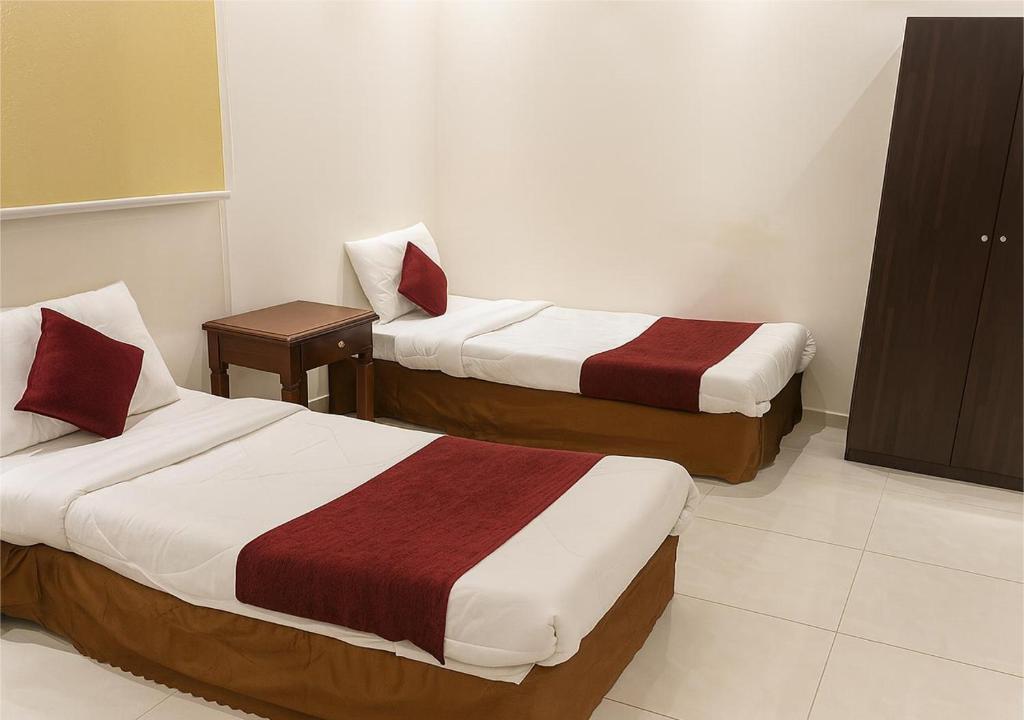 une chambre d'hôtel avec deux lits et une table dans l'établissement فندق مناسك وقف عبدالقادر نصير, à La Mecque