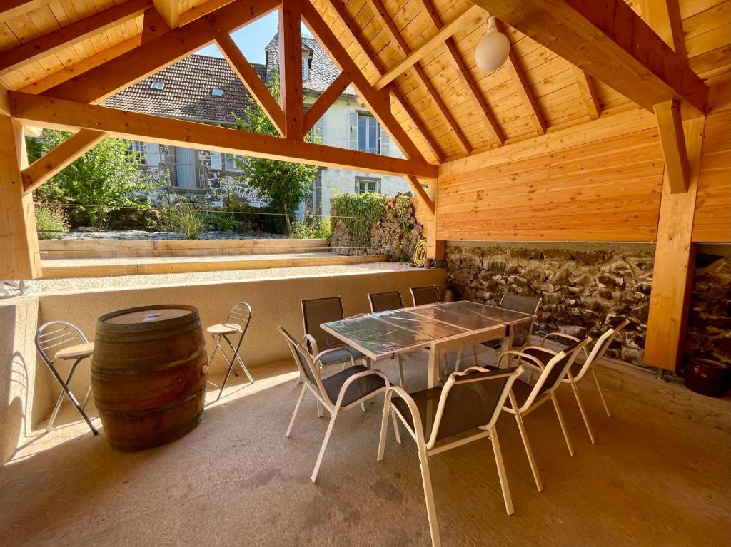 d'une terrasse avec une table, des chaises et un tonneau. dans l'établissement Maison de caractère rénovée avec terrain de pétanque, à Saint-Cirgues-de-Jordanne