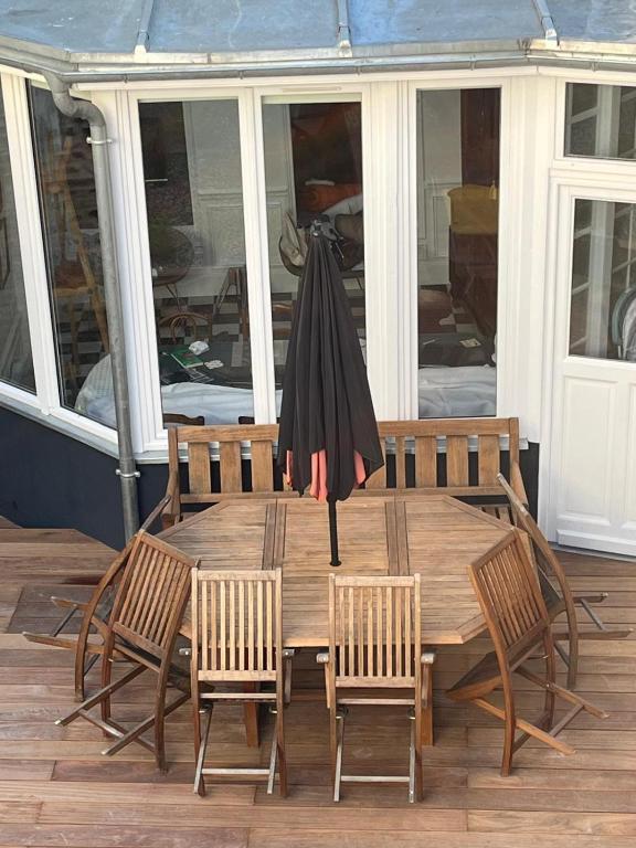 une table en bois avec des chaises et un parasol sur une terrasse dans l'établissement Les Flobarts - grande maison de famille en centre ville à 50m de la baie, à Saint-Valery-sur-Somme