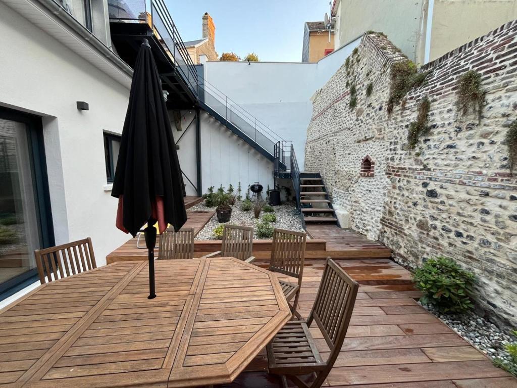 una sombrilla sobre una mesa de madera en un patio en Les Flobarts - grande maison de famille en centre ville à 50m de la baie, en Saint-Valery-sur-Somme