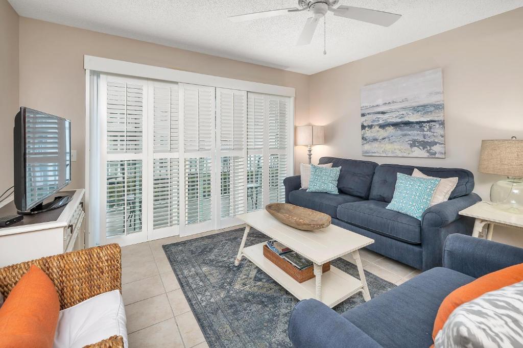 a living room with a blue couch and a tv at Beach Club #223 in Saint Simons Island