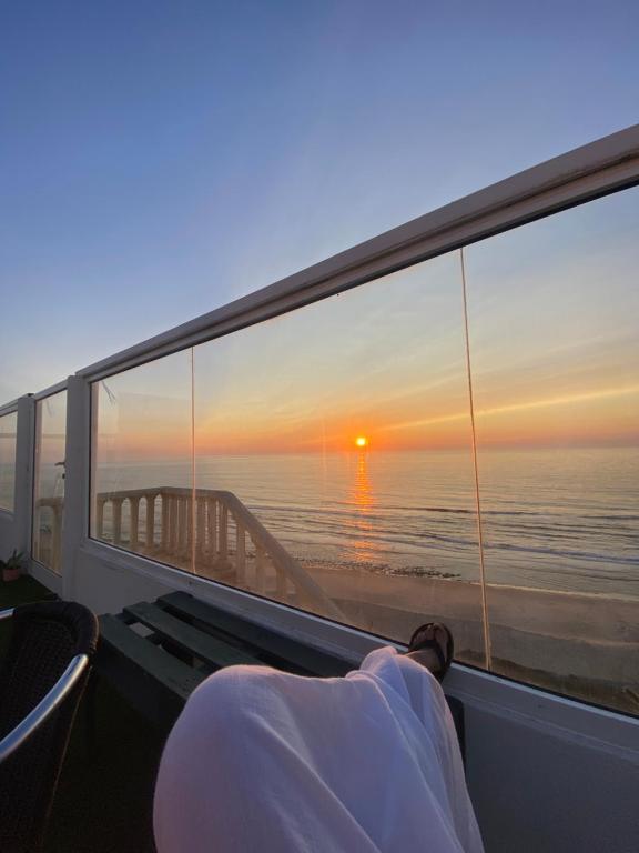 a person laying on a boat looking out a window at a sunset at Albergaria Pedra D'Ouro in São Pedro de Moel