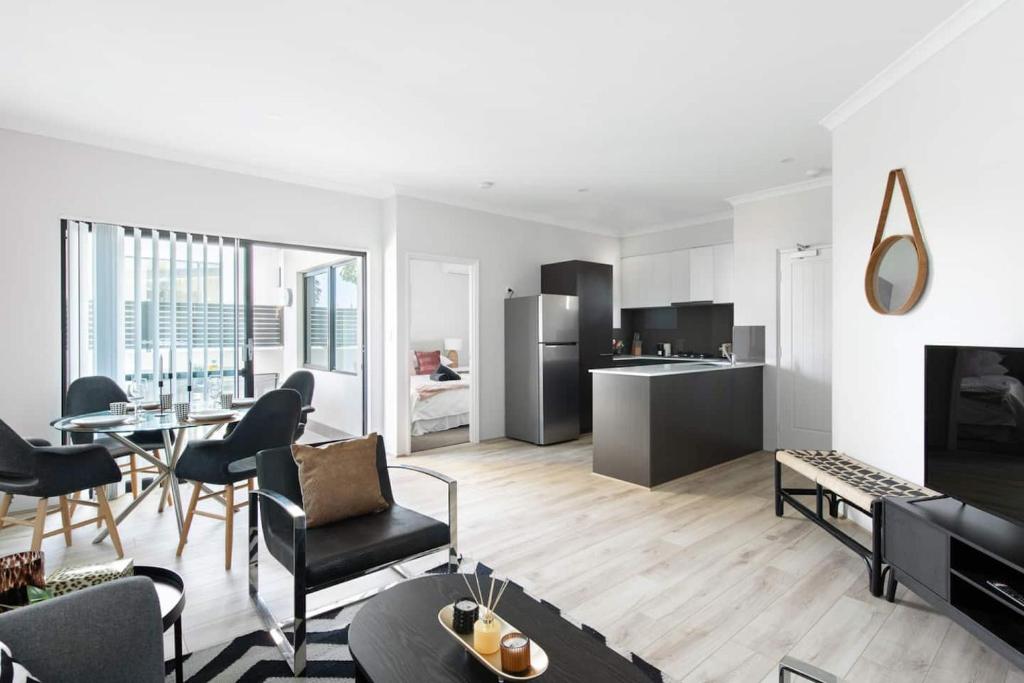 a living room with a table and chairs and a kitchen at Chic Exec 2bdr 2bath -River,FREO,Parking,AC in Perth