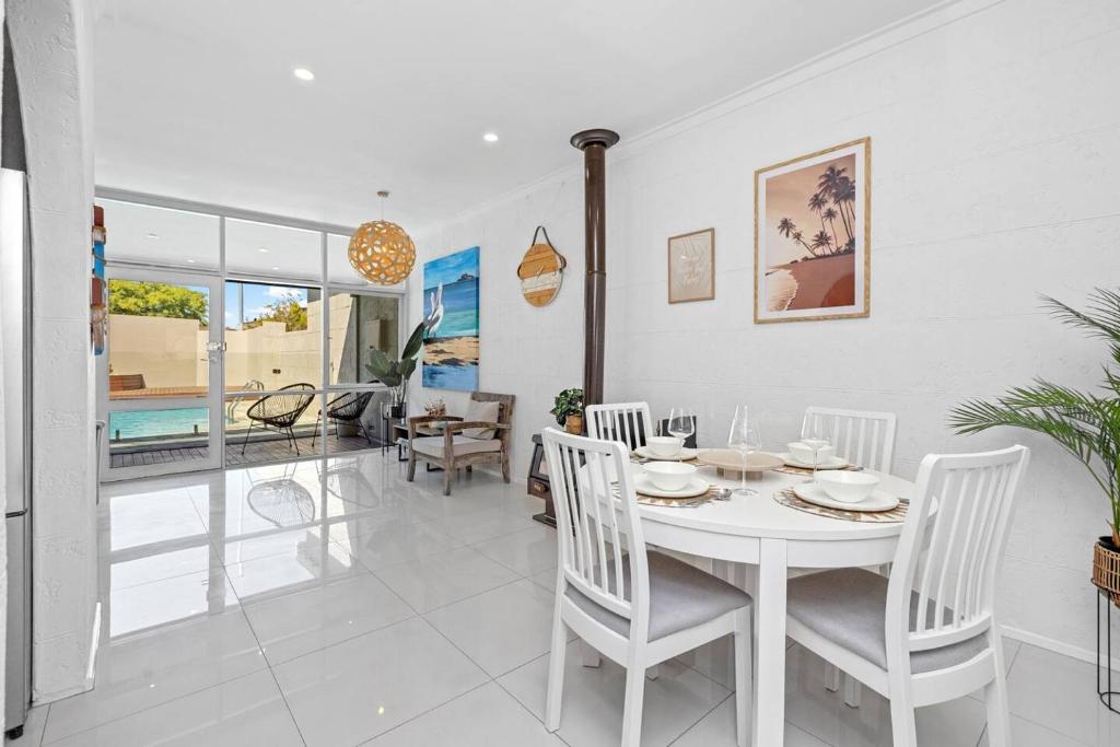 a white dining room with a white table and chairs at Tropical Zen Stylish Beach-Inspired Home w Pool in Perth
