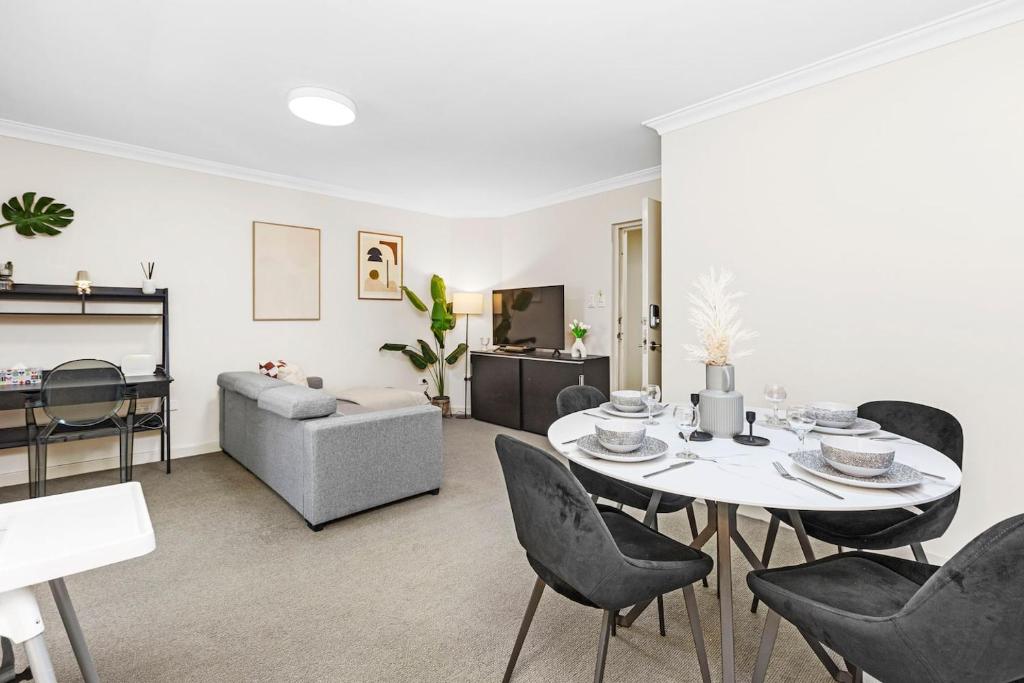 un soggiorno con tavolo, sedie e divano di Stylish City 1bdrm Apt Perth Heart 2 mins river a Perth