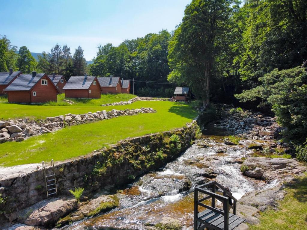 a stream with houses in the background next to a field at MorsoChatki - balia, sauna, garden party, plaża in Jelenia Góra