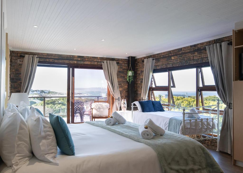 a bedroom with two beds and large windows at White Shark Guest House in Gansbaai
