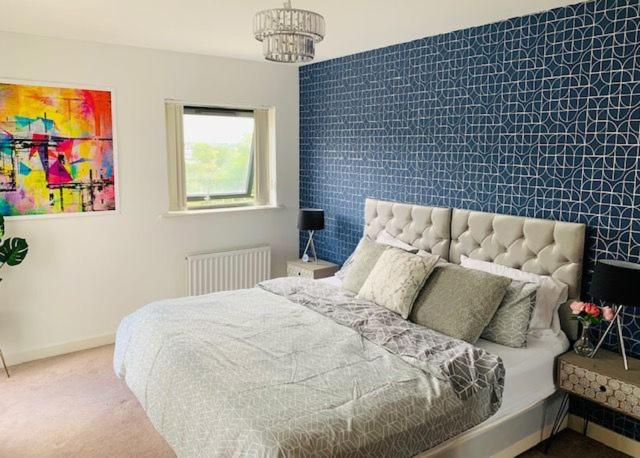 a bedroom with a bed with a blue accent wall at Atom, Large 4 to 5 Bed House in East London, Sleeps 12, Garden, Parking, ideal for Contractors, Large Groups, Travellers in Barking