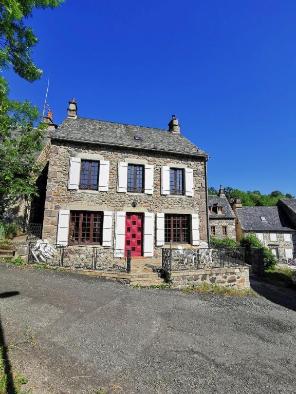 une ancienne maison en pierre avec une porte rouge dans l'établissement Familial House Dellac-Mathieu in mountain village Cantal, à Saint-Saturnin