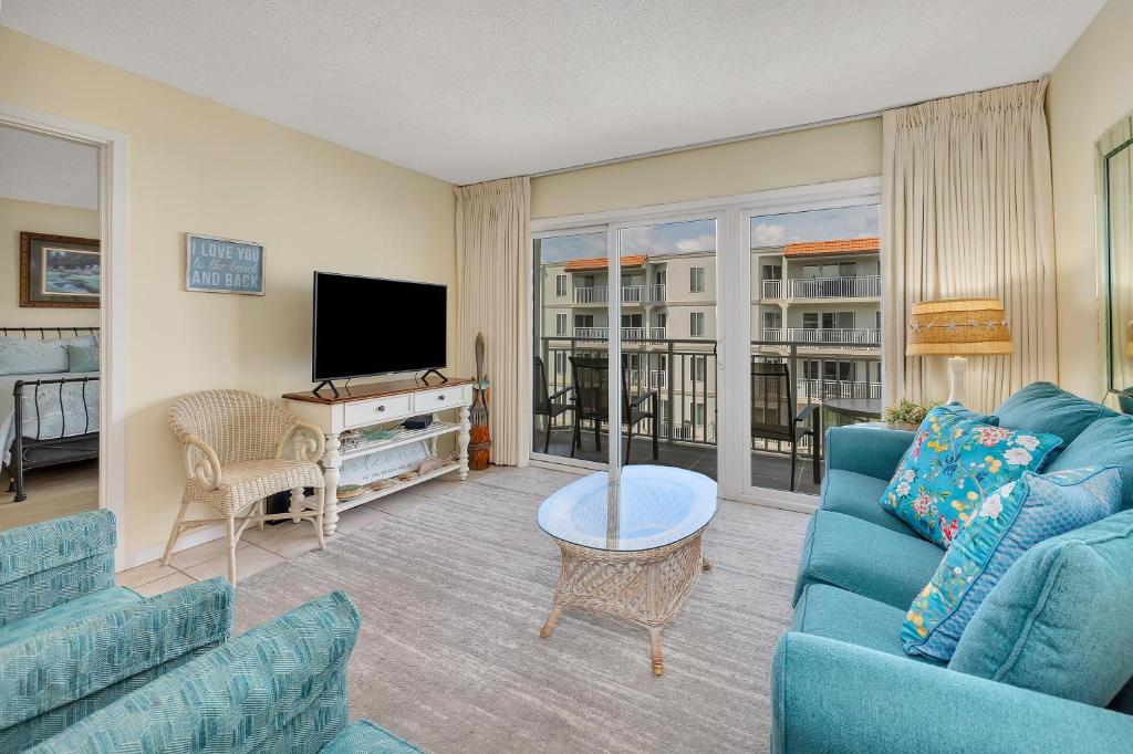 un salon avec un canapé bleu et une télévision dans l'établissement Beach Club #313, à Île de Saint-Simon