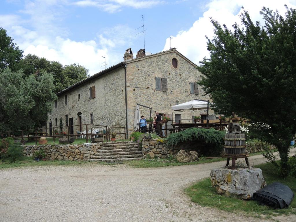 un gran edificio de piedra con gente de pie delante de él en Agriturismo I Sassi Grossi, en Corciano