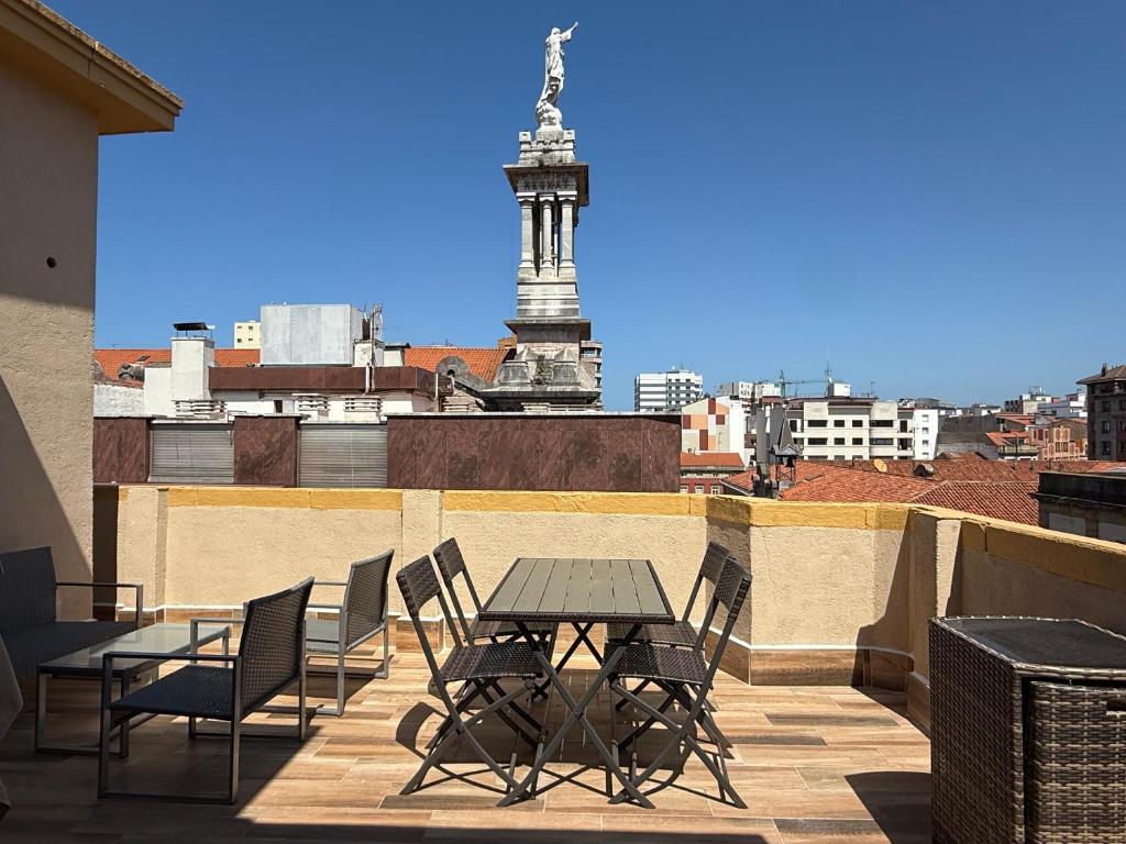 a patio with a table and chairs on a roof at Ático Jovellanos in Gijón
