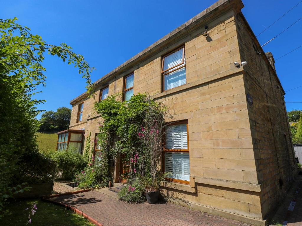 a brick house with ivy on the side of it at The Old Post Office - Pet Friendly Group Stays in Holmfirth in Holmfirth