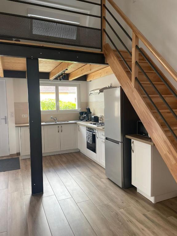 une grande cuisine avec des placards blancs et un escalier dans l'établissement Maison neuve toute équipée, à Mervans