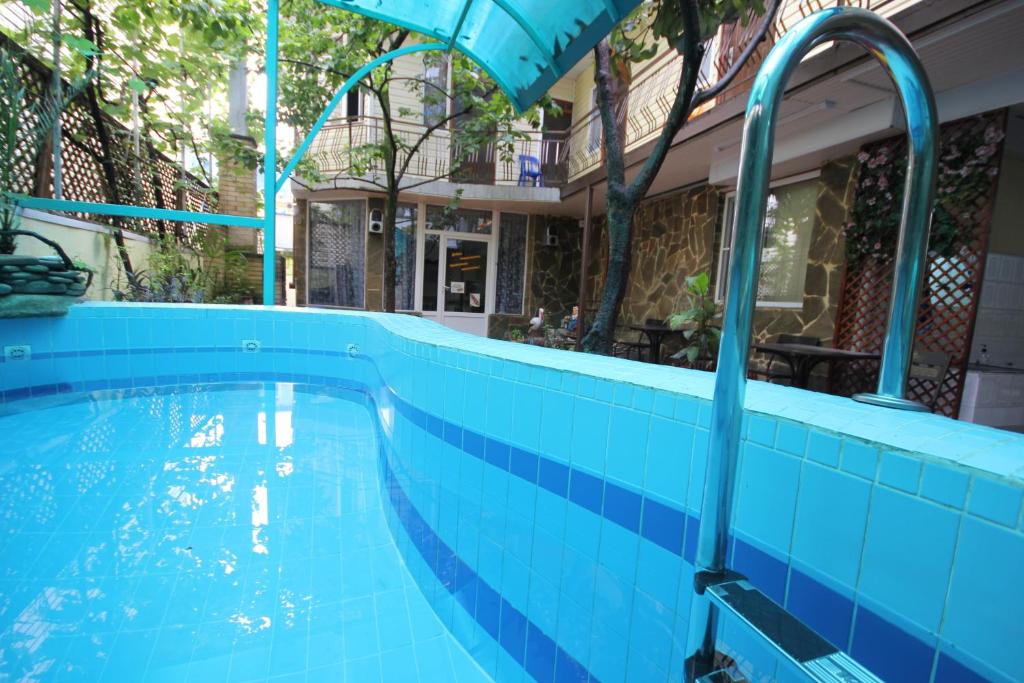 una piscina azul frente a un edificio en Adler Home, en Adler
