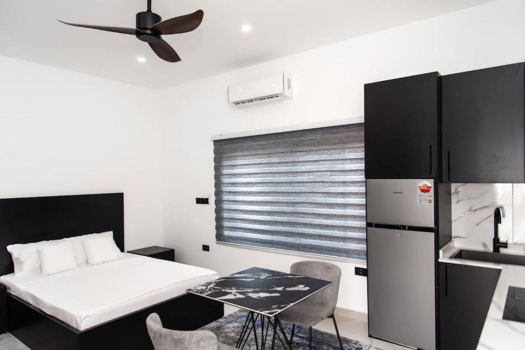 a bedroom with a bed and a table and a refrigerator at The Kottage Studio Apartment A in Accra