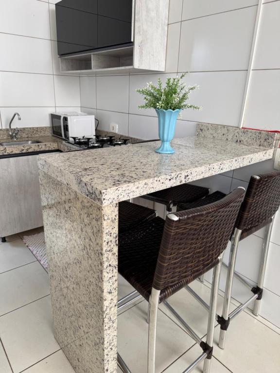 a kitchen with a counter with chairs and a vase with a plant at Apartamento maringa in Maringá