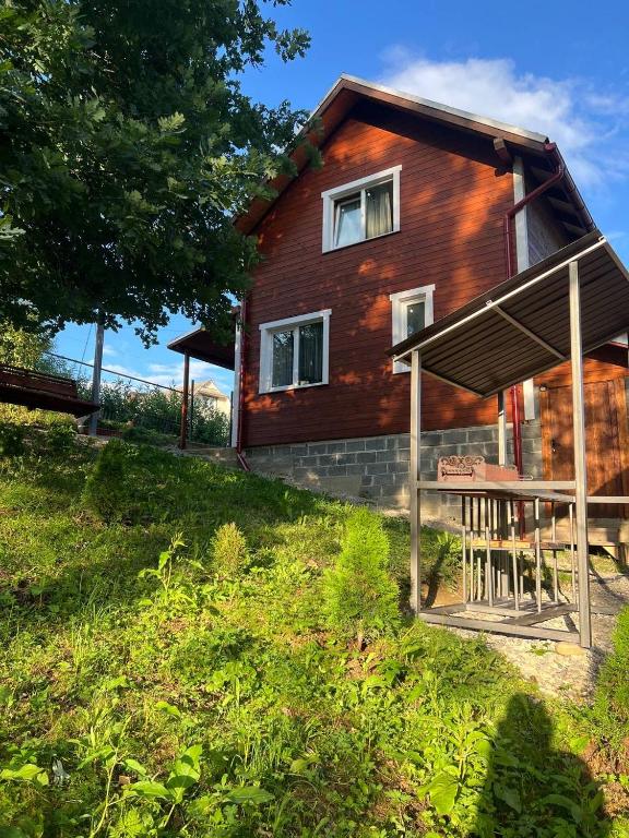 a wooden house on a hill with a green yard at Карпатський котедж Karpatian cottage in Vorokhta
