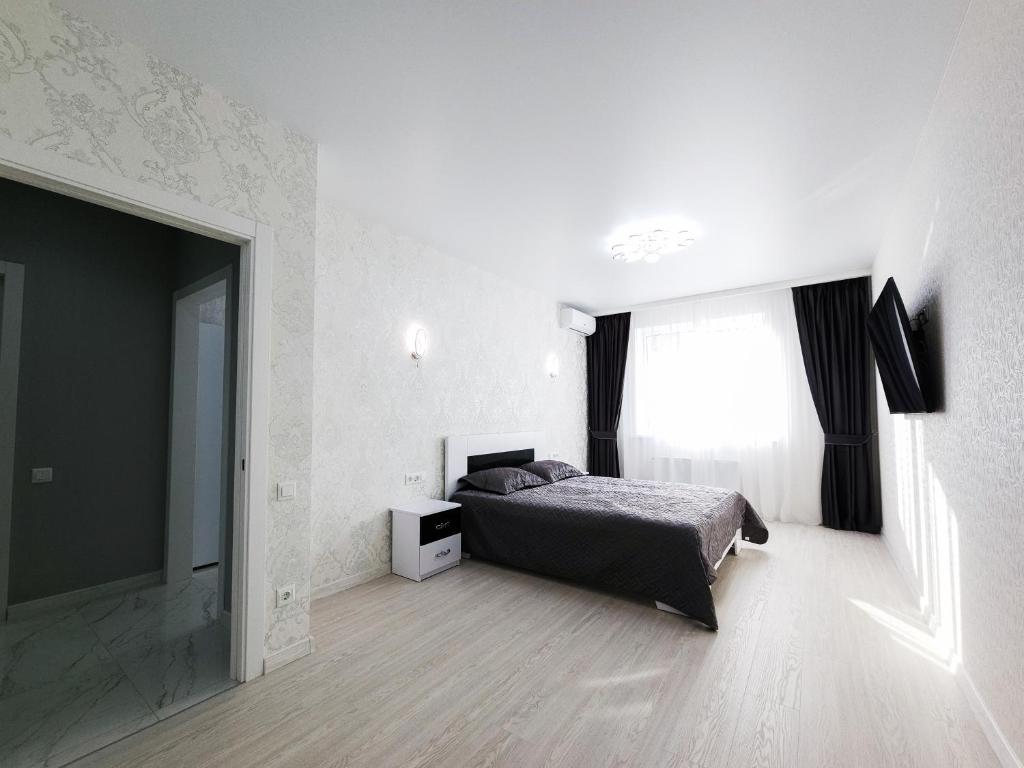 a white bedroom with a bed and a window at Апартаменты Kadorr 59 in Odesa