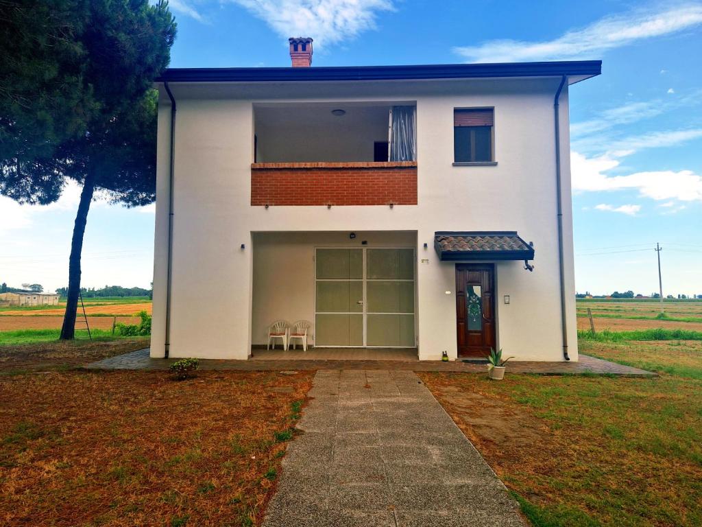 a white house with a large garage and two chairs at Ca' Elena in Codigoro