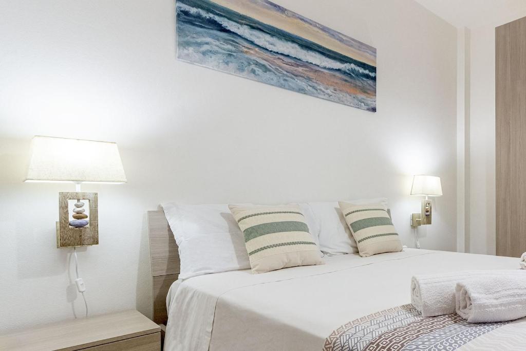 a white bedroom with a bed and a painting on the wall at Nura's - Luna Charme House in Alghero