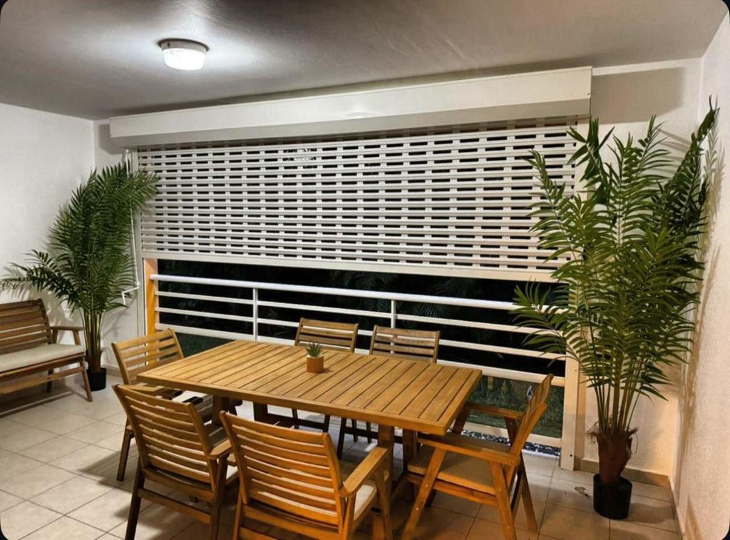 a dining room with a wooden table and some plants at Élégance in Baie-Mahault
