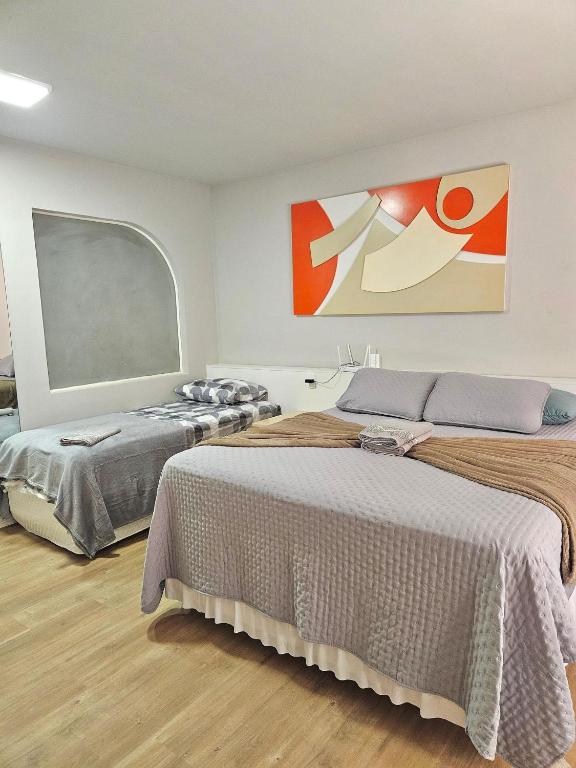 a bedroom with two beds and a large painting on the wall at Saint Sebastian Flat 716 - Com Hidro! até 3 pessoas, Duplex, no centro in Jaraguá do Sul