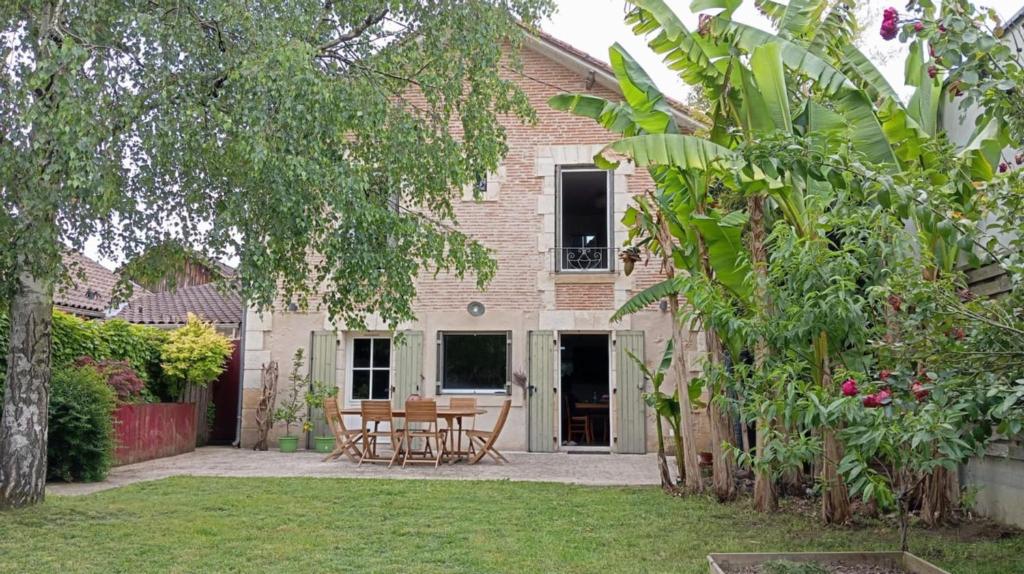 een huis met een tafel en stoelen in de tuin bij Les bananiers in Bergerac