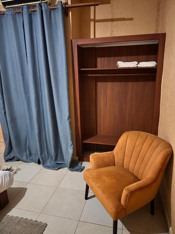 krzesło w pokoju z niebieską zasłoną w obiekcie Bastos flat w mieście Jaunde