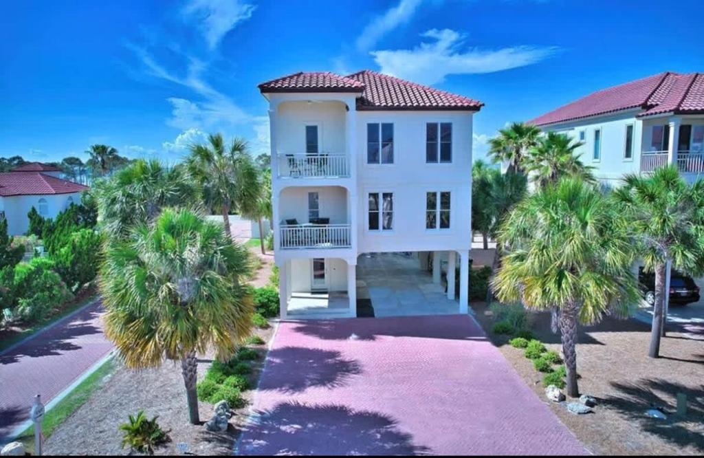 a white house with palm trees in front of it at Serenity Sunset 5Bedroom Dog Friendly Beach House on St George Island in Eastpoint