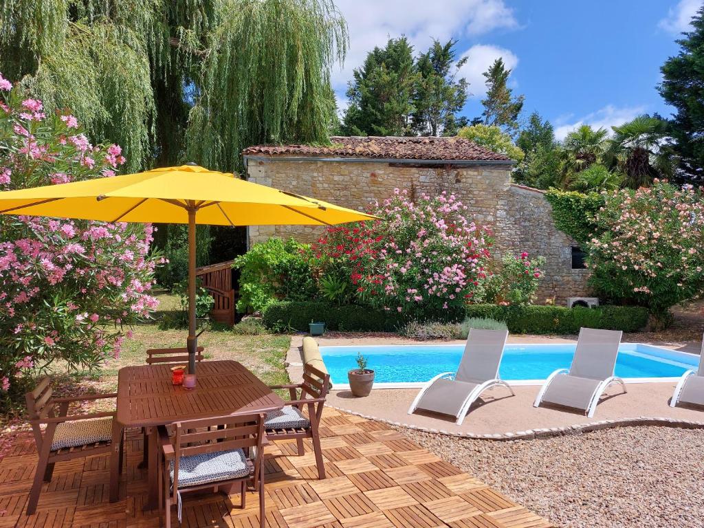 une table et des chaises avec un parasol à côté d'une piscine dans l'établissement Pause Charentaise chambre avec piscine, à Cravans