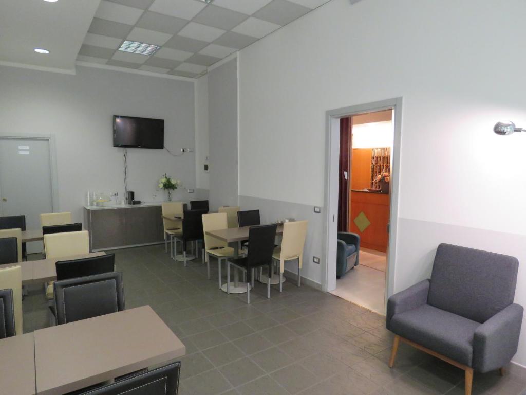 a waiting room with tables and chairs and a tv at Hotel Marta in Forlì
