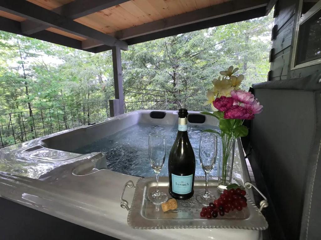 a bottle of wine and glasses in a bath tub at The Treehouse TN Honeymoon Cabin HOT TUB - in BSF! in Jamestown