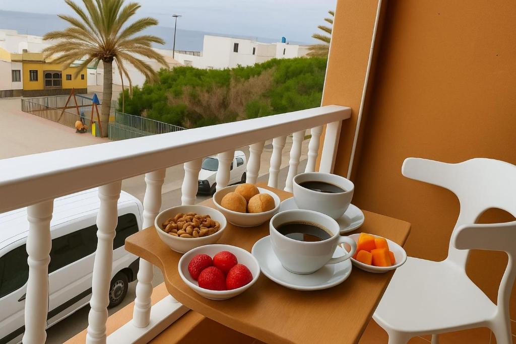 グラン・タラハルにあるThe RITA Home FUERTEVENTURA Gran Tarajalのバルコニーに置かれたコーヒーカップとフルーツボウルが乗ったトレイ