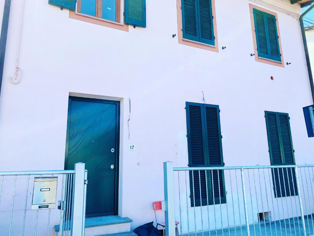 Una puerta azul en un edificio blanco con persianas verdes. en Casa Palace, en Certaldo