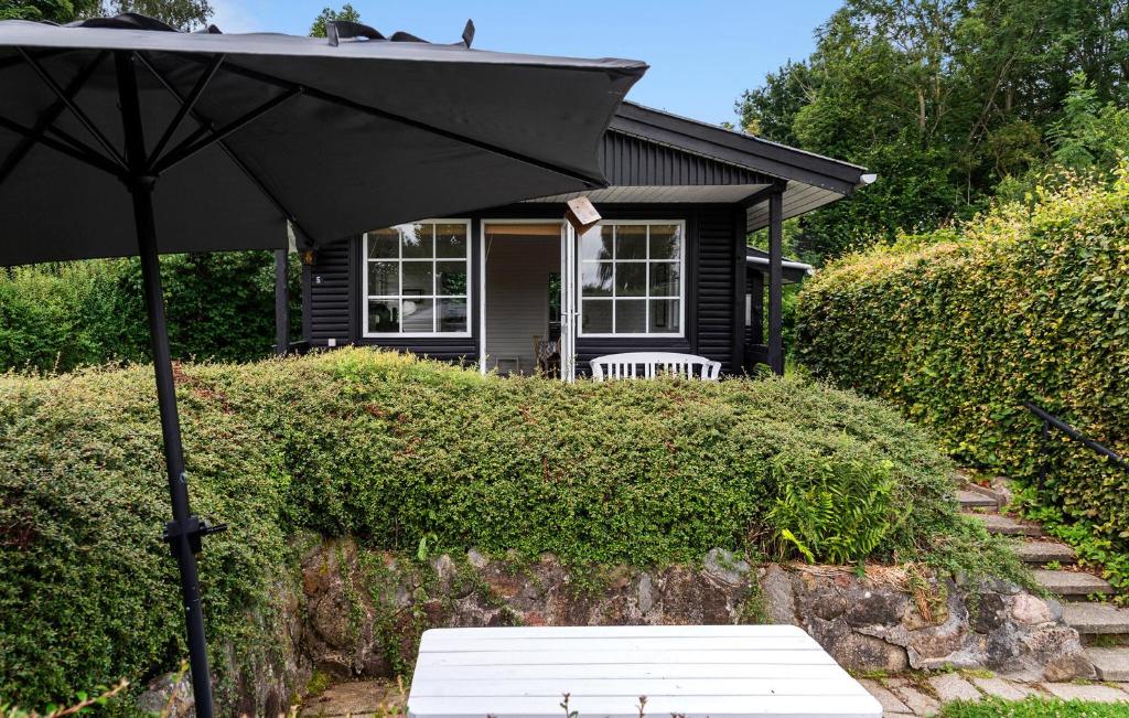 a black umbrella and a bench in front of a house at Pet Friendly Home In Aabenraa With Wifi - F07406 in Aabenraa