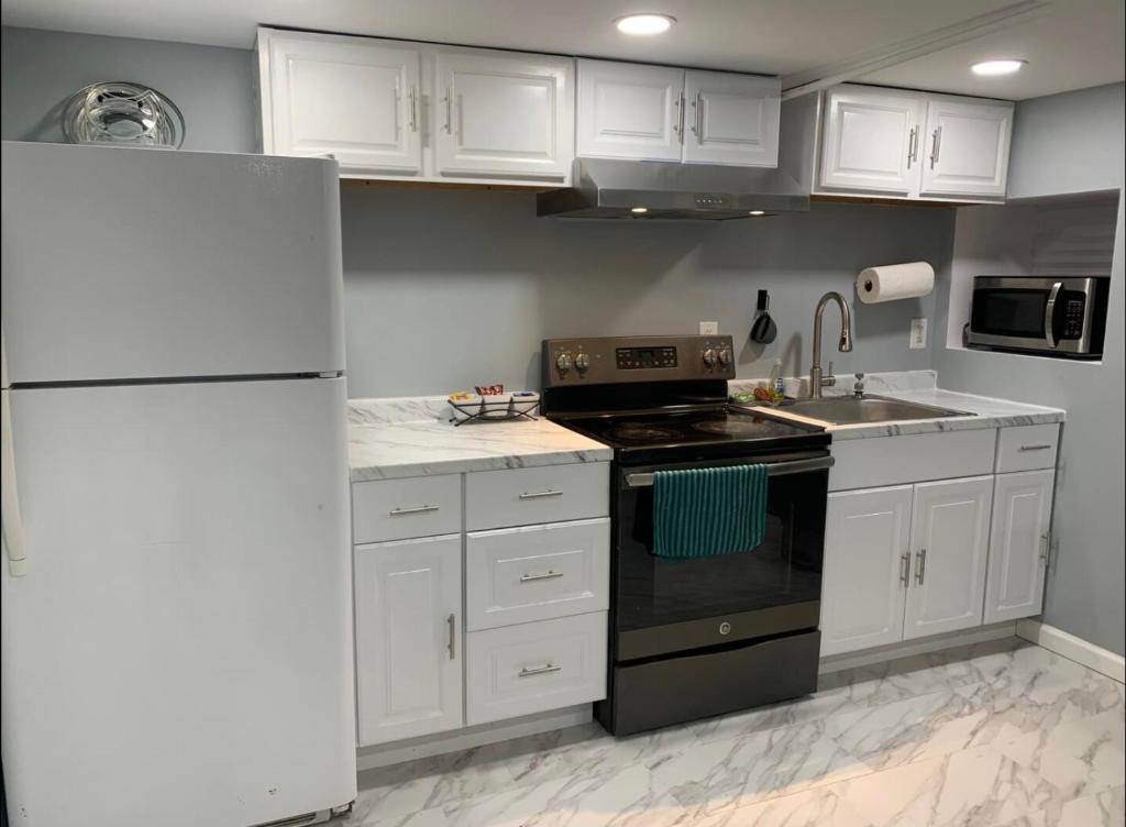 een keuken met witte kasten en een zwarte kachel bij A Cozy Corner with kitchen and parking in Drexel Hill