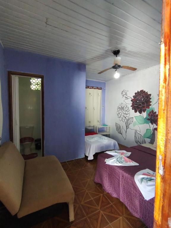 a room with two beds and a couch and a blue wall at Pousada Villa da Música Beira Mar Dàlia Pontal Centro in Paraty