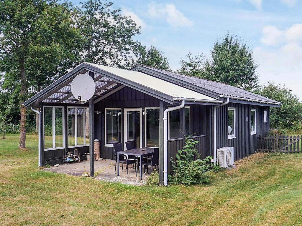 un cobertizo negro con una mesa en un patio en 2 person holiday home in Thyholm-By Traum, en Thyholm