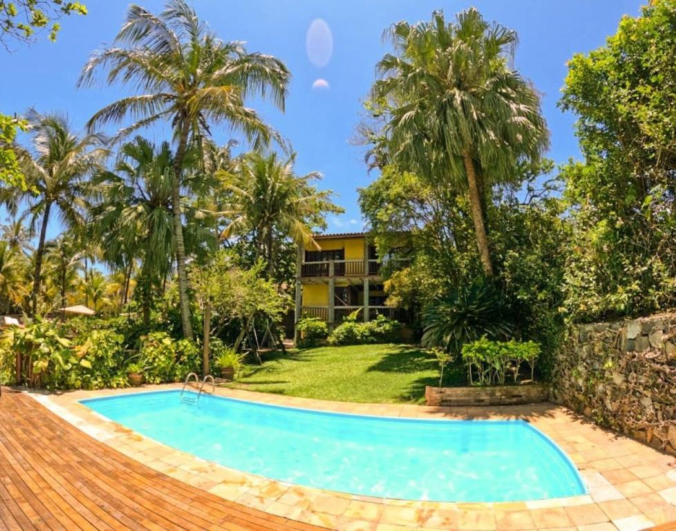 a swimming pool in front of a house with palm trees at Casa Janaina Ilhabela in Ilhabela